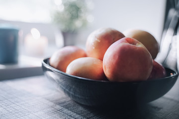 a plate of peaches on the table in front of the white windowsill