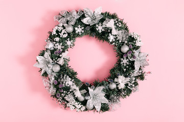 Christmas holiday composition. Christmas wreath and silver decorations on pastel pink background....
