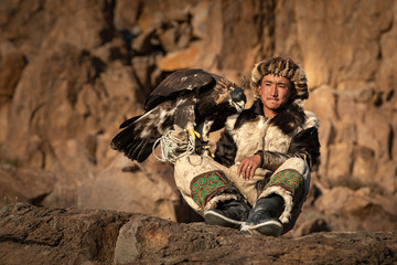 Portrait of a young kazakh eagle hunter with his majestic golden eagle in the steppe. Ulgii,...