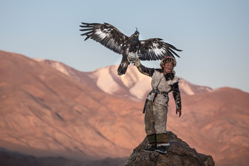 Portrait of a young kazakh eagle hunter with his majestic golden eagle in the steppe. Ulgii,...