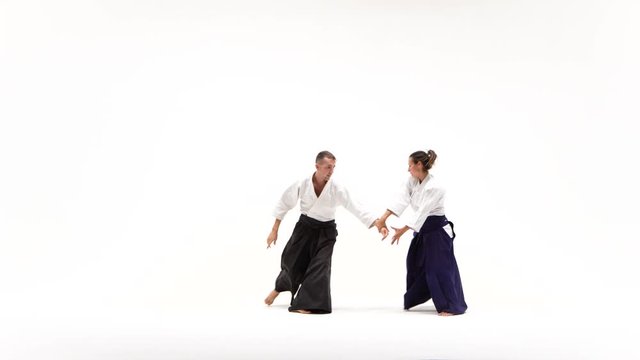 Man, woman in kimono performing aikido techniques, isolated on white.