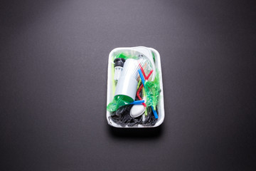Set of plastic waste in a packed tray on a black isolated background. The problem of ecology and environmental pollution.