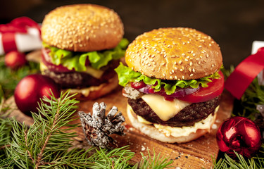 Christmas dinner for two, two homemade hamburgers with salad and cheese on a stone table with a Christmas tree and Christmas toys