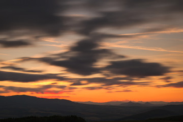Red sunset with cloudy sky and mountains in the background