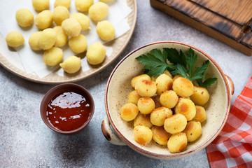 Roasted and uncooked potato gnocchi, elevated view over beige stone background, horizontal shot