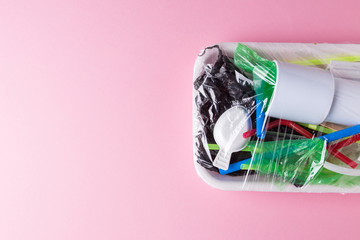 Set of plastic waste in a packed tray on a pink isolated background. The problem of ecology and environmental pollution.