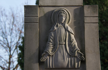 Monument and candles in the cemetery. All Saints Day in Poland. Stone sculpture.