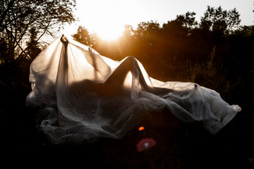 Slender nude girl, covered by a cellophane film, through which only her silhouette is visible and...