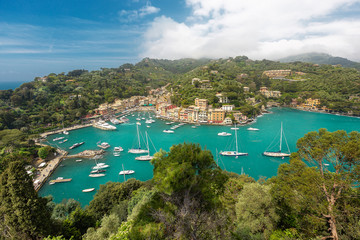 Colorful italian village Portofino in the province of Liguria, Italy - Sea bay marina port with boats and yachts and beautiful colored houses - Tourists walking on sidewalk