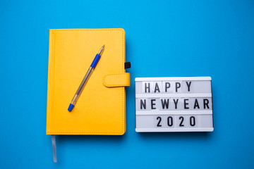 Diary of yellow color on a blue isolated background close-up. Happy New Year sign. 2020.