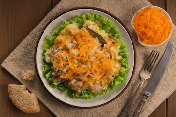 Pilaf in a plate on wooden background, top view