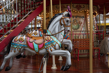 Merry go round. Fairytale painted white toy horse of vintage carousel in French style. Retro colorful illuminated merry-go-round with golden shiny lights. Kids playground at Christmas market in Europe © Ninel