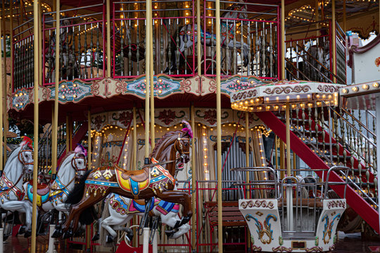 Carousel in park. Gorgeous vintage carousel with toy horses and shiny golden lights. Circle merry-go-round at funfair in European city. Fairytale retro ornate roundabout swings. Happiness concept