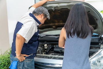 woman who owns the car standing and looking for auto mechanic Check the engine to find the cause.