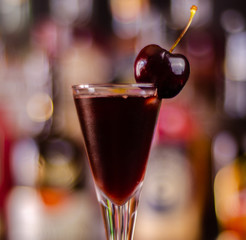 Cherry liqueur and juicy ripe cherries on the table in the bar, an elegant serving of sweet drink in the restaurant
