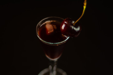 Cherry liqueur and juicy ripe cherries on the table in the bar, an elegant serving of sweet drink in the restaurant
