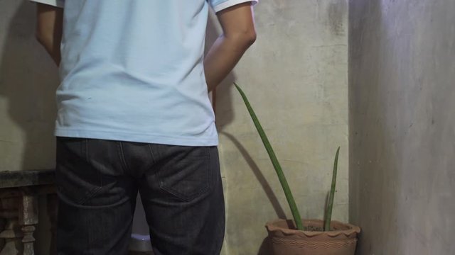A man peeing by using urinal in men public toilet