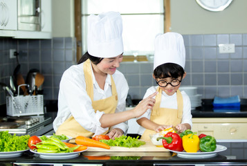 Happy family Asian woman young mother with son boy cooking healthy salad for the first time. first lesson and healthy lifestyle concept.