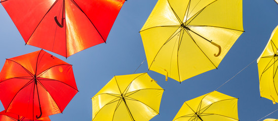 Colourful umbrellas urban street decoration. Hanging colorful umbrellas over blue sky, tourist attraction