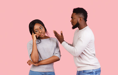 Black couple fighting over pink studio background