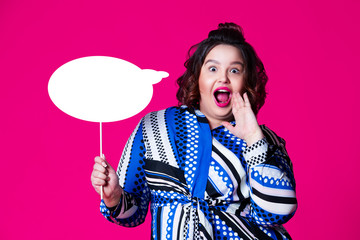 Plus size model with wide open mouth holding speech bubble on red background