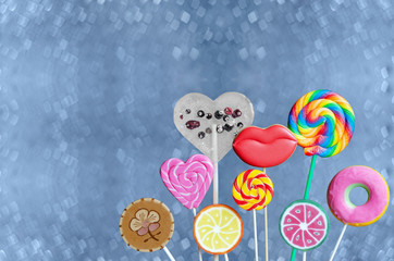 Colorful lollipops and cookies in the form of lips, on a blurred blue background bokeh