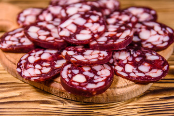 Cutting board with sliced salami sausage on a wooden table