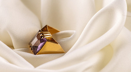 Gold ring with alexandrite on the background white silk. Macro for Closeup. High resolution