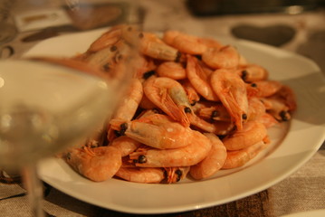 a glass of white wine and a plate of shrimp in focus