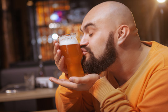 Close up of a bearded man kissing glass of delicious beer at the pub