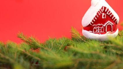 Christmas composition Christmas decorations, toy in the form of a house, fir branches with a red background. Flat design, side view, copy space. Place for text.