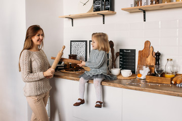 Happy family in the kitchen. Happy young girl with her mother in kitchen at home.