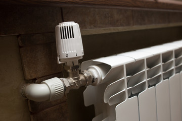 White radiator in the bathroom close-up. Heating. Tiled gray wall.