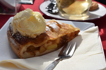 Delicious apple strudel with cream serviced on a table outside