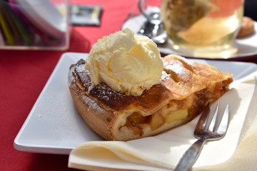 Delicious apple strudel with cream serviced on a table outside
