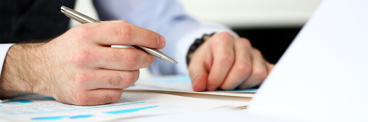 Clerk man at office workplace with silver pen in arms