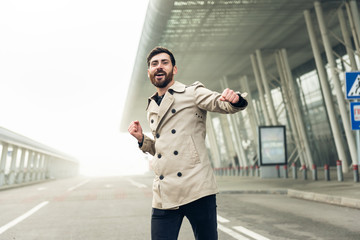 Fototapeta premium Cheerful and Happy Businessman is Actively Dancing on a Street . He's Wearing a Grey Suit. Sunny Day.