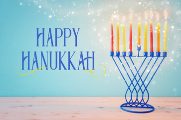 Religion image of jewish holiday Hanukkah background with menorah (traditional candelabra) and candles over pastel blue background