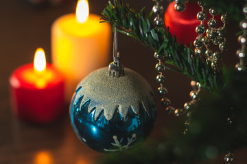 Christmas decorations on xmas tree and candles burning on a table.
