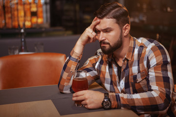 Depressed young man drinking alone at the bar. Handsome man looking drunk, sitting alone at the bar...