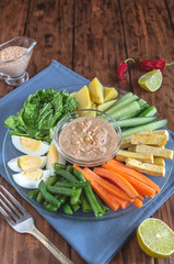 Gado gado vegetable salad with eggs and tofu on a wooden table.