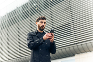 Young businessman typing text message on his way to work.