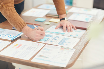 Cropped portrait of unrecognizable businessman analyzing statistics graphs and charts while planning project in office, copy space