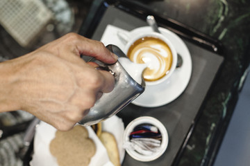 The hand of a bar man making a nice hot cappuccino in Rome