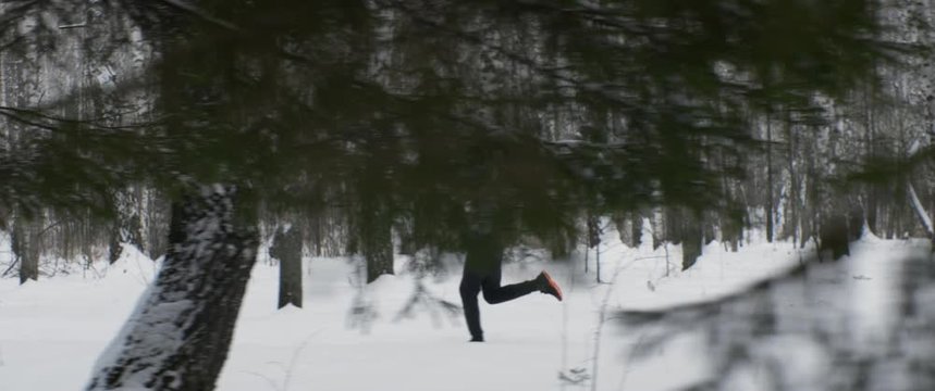 Young Caucasian male jogger runs long distance in forest or park. Sprinting fast exercising cardio workout training. Man runs at high speed. Anamorphic tracking wide shot