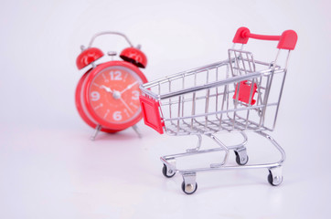 Shopping cart and classic alarm clock on white background. Sale time buy mall market shop consumer...