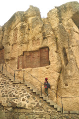 Woman on the Staircase with a Number of Khachkar or Cross-stones on the Cliff Wall, Geghard Monastery, Armenia 