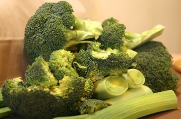 Fresh vegetables in winter on the green table: green heads of garden cabbage broccoli, onion pods of leeks against 