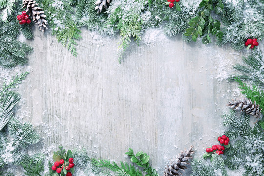 Christmas and New Year background with fir branches and snowfall on wooden white board
