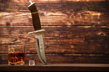 Whiskey with ice or brandy in a glass and a square carafe on an old wooden background. Whiskey with...